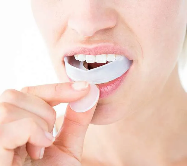 woman puts mouthguard into mouth