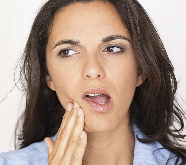 woman touches face in pain